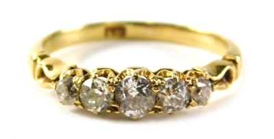 A five stone diamond dress ring, set with five old cut diamonds of graduating size, the largest approximately 0.10 carats, the smallest 0.03 carats, with twist design shoulders, on yellow metal band marked 18ct, ring size O, 2.9g all in.