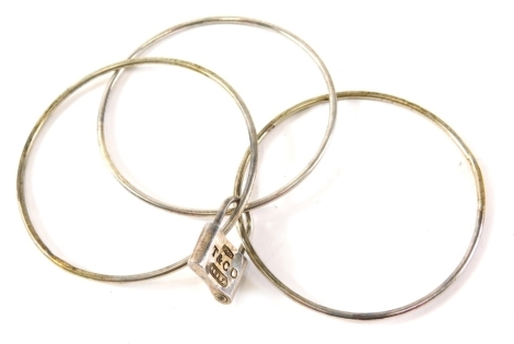 A set of Tiffany & Co bangles, comprising three bangles locked with padlock, the padlock stamped T & Co 925, 28.3g, approx 7cm diameter.