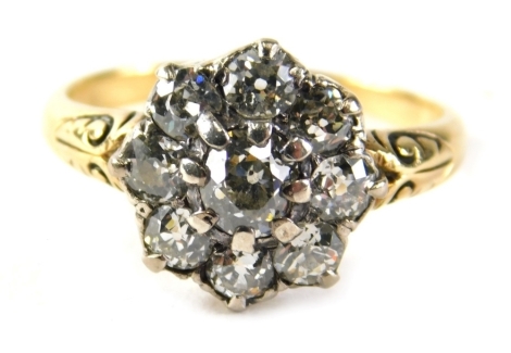 A Victorian dress ring, set with a floral cluster of tiny diamonds, on yellow metal scroll shoulders, unmarked, believed to be 18ct, ring size N½, 3.3g all in.