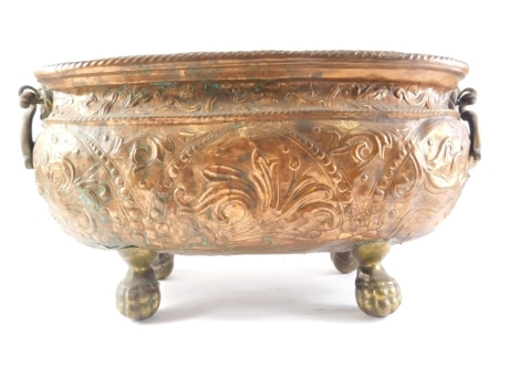 A Continental brass and copper jardiniere, with embossed decoration, foliate scrolls, etc., flanked by pierced handles on ball and claw feet, 62cm wide.