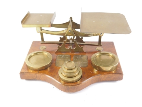 A large set of postal scales, and some weights, the shaped oak base applied with two plaques for postal rates for letters and parcel post rates, 37cm wide.