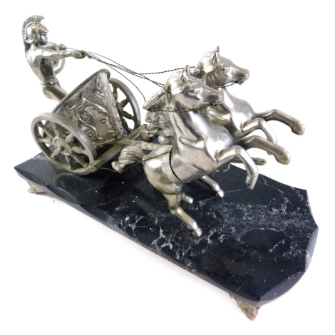 A silver plated model of a figure riding chariot with two horses, on a marble finish base terminating in leafy feet, 25cm high.