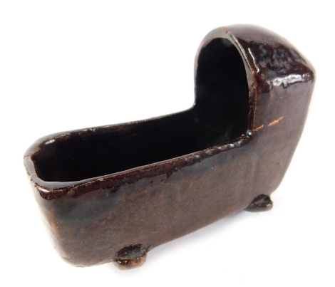 A miniature late 19thC treacle glazed pottery crib, 10cm high.