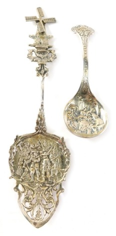 A Dutch white metal serving spoon, with windmill and turned handle, part repousse and pierced bowl, 20cm wide, and a further Dutch silver spoon heavily repousse decorated. (2)