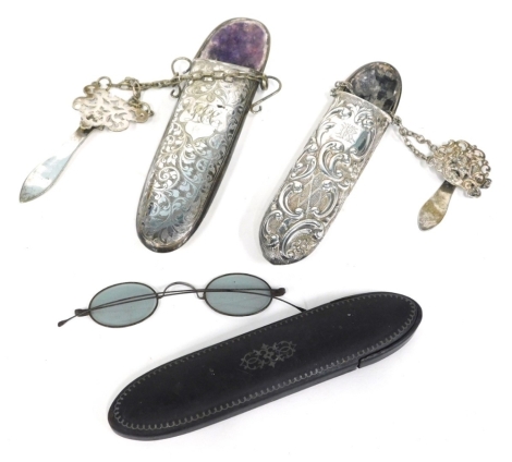 An Edwardian spectacle case, of oblong form, with a velvet lined interior, chased with a scroll decoration, initialled cartouche, 19cm long, a repousse decorated spectacles case and another ebonised with a pair of metal framed spectacles with plain side b