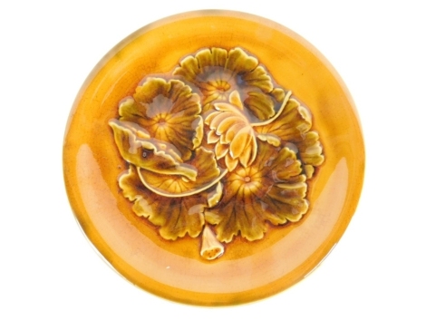 A Linthorpe pottery plate, with Christopher Dresser signature mark, raised with flowers no. 622, impressed marks beneath, 24cm diameter. Auctioneer announce: Slight loss to leaf, glaze pops in some places.