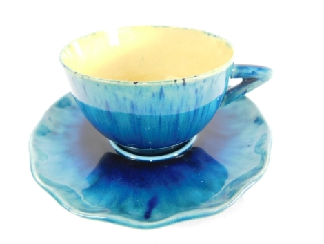 A Linthorpe pottery tea cup and saucer, in turquoise and blue glazes, the cup with angular handle, 5cm high, each numbered 1427, impressed marks beneath. (2)