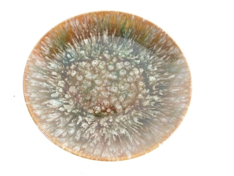 A Linthorpe pottery plate, with pudding bowl base in speckled decoration in green, brown and blue, no 930, marked H impressed marks beneath, 19cm diameter.