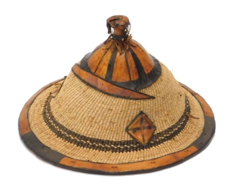 An Oriental rope work hat, with leather embellishments, partly decorated in black with chin strap, 30cm high.