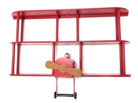 A decorative child's wall shelf formed as a biplane, predominately in red, 80cm high.