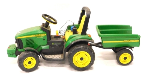 A child's John Deere two speed battery powered tractor, 60cm high, with trailer, leads and other accessories.