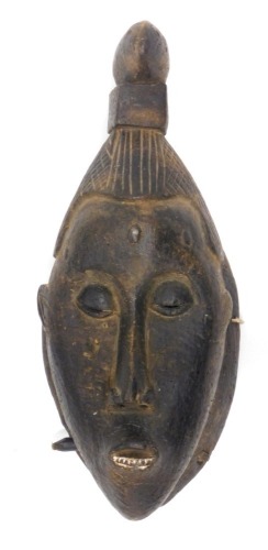 A 20thC Baule tribal wall mask, with elaborate hair, 36cm high.