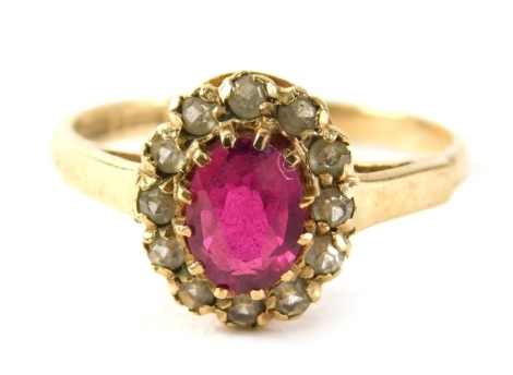 A 9ct gold garnet and cz cluster ring, the oval garnet surrounded by cz in claw setting on a yellow metal band with V splayed shoulders, ring size P, 2.3g all in.