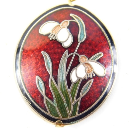 An enamel pendant and chain, the red oval enamel pendant set with snowdrops, 3cm high, in a plated loop clasp on a gold plated chain, 14cm long.