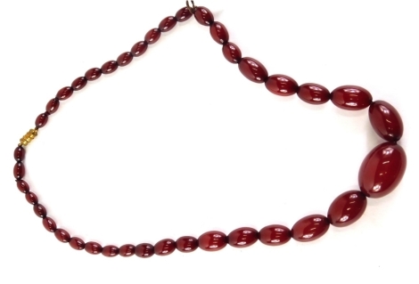 A red amber beaded necklace, the largest bead 3cm wide, the smallest 1cm wide, on string strand with a plated clasp, 48.8g all in.