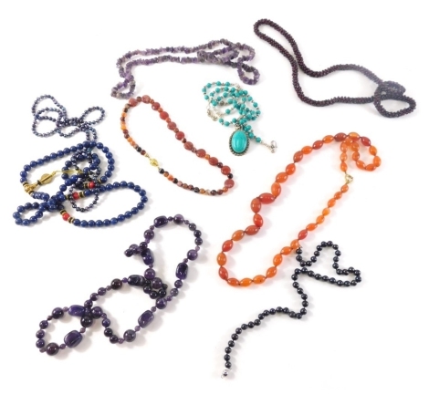 A group of hardstone necklaces, comprising an orange oblong beaded necklace with gold plated clasp, two rough cut amethyst necklaces, garnet beaded necklace, lapis lazuli necklace, turquoise pendant and chain, etc. (1 tray)