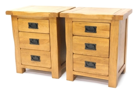 A pair of oak bedside cabinets, each with three drawers and a ebonised metal handle, on stiles, 58cm high, 50cm wide, 42cm deep.