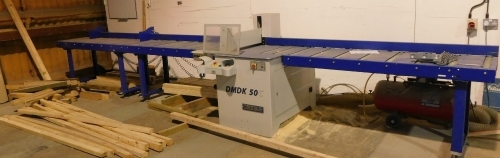 A Rema DMDK-50C cross cut saw with roller platform, the bed being 4.1 metres to the left of the cut and 2.6 metres to the right, including unit block, three phase. VAT is also payable on the hammer price of this lot.