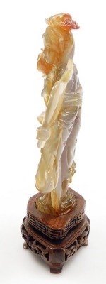 A Chinese agate figure of Guanyin, modelled standing holding a hand mirror, and a lotus flower, raised on a hardwood base, 16cm high. - 7