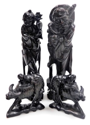 Two Chinese hardwood figures of deities, with silver wirework inlay, 29cm high and 28cm high, and two figures modelled as boys riding on buffaloes, 12cm wide. - 18