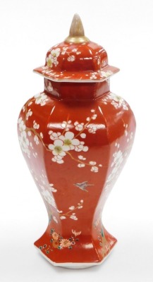 A late 19thC Japanese porcelain vase and cover in the Chinese style, of faceted baluster form, decorated with prunus on an iron red ground, 31cm high. - 10