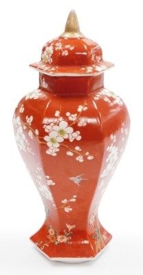 A late 19thC Japanese porcelain vase and cover in the Chinese style, of faceted baluster form, decorated with prunus on an iron red ground, 31cm high. - 12