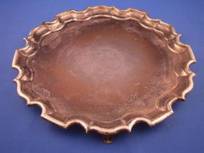 A silver salver with a pie crust border on three scrolling feet bearing monogram to centre