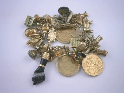 A heavy charm bracelet with thirty six attached charms including one Victorian