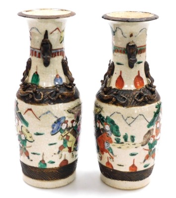 A pair of Chinese crackle glaze vases, of baluster form, with applied dog of fo handles and chilin to the neck, the body depicting a battle scene with figures on horseback, four character mark, 29.5cm high. - 2