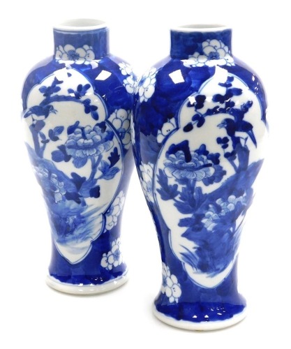 A pair of 19thC Chinese porcelain blue and white vases, of baluster form with a raised neck, each decorated with reserves to front and verso of a bird on flowering branch, on a cracked ice ground decorated with prunus blossom, Kangxi four character mark,