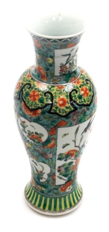 An early 20thC Chinese famille vert porcelain vase, of baluster form with a flared neck, decorated with reserves of birds and flowering branches, against a floral decorated green ground, unmarked, 30cm high.