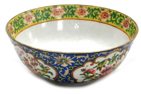 A 19thC Chinese porcelain bowl, decorated in coloured enamels, the exterior predominately blue with repeating reserves of birds and flowering branches, the interior centrally decorated with a dragon with a yellow ground upper band with repeating flowers, 