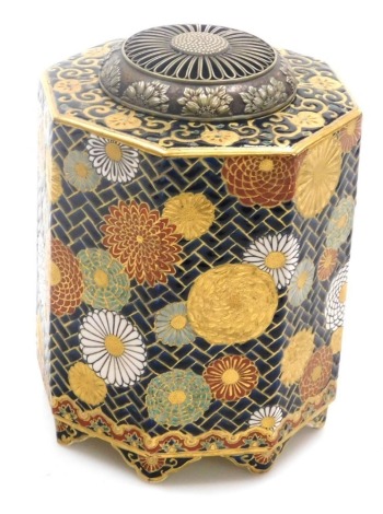 A Japanese Meiji period Satsuma earthenware pot pourri jar and cover, with a pierced metal lid decorated with raised flowers, the octagonal body decorated with flowers against a dark blue hatched ground, with gilt highlights on eight shaped feet, signed a