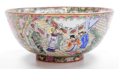 A late 20thC Cantonese famille rose porcelain bowl, decorated with reserves of figures in a garden, butterflies and flowers, against a gilt ground decorated with flowers, scrolls and butterflies, faux six character Qianlong mark, 30cm wide.