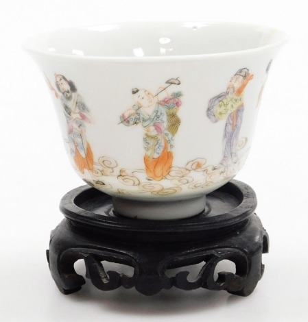 A Chinese porcelain teabowl, decorated with the Eight Immortals, six character mark Yongzheng mark to underside, 10cm diameter, on a hardwood stand.