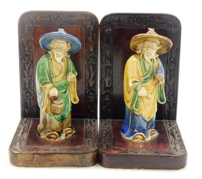 A pair of Chinese hardwood bookends, set with mudman figures and a carved floral border, 16cm high. - 2