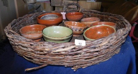 A wicker basket, of circular form with handles, containing a quantity of terracotta bowls, some painted. Note: VAT is payable on the hammer price of this lot at 20%.