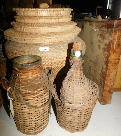 A woven storage basket, with lid, 42cm high, various loose lids, two wicker storage containers with glass liners, and a hardwood chopping board, 71cm x 41cm. Note: VAT is payable on the hammer price of this lot at 20%.