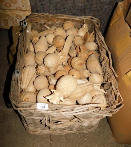 A wicker log basket, 37cm high, 64cm wide, containing a quantity of carved treen fruit, to include pineapples, bananas, apples, etc. Note: VAT is payable on the hammer price of this lot at 20%.