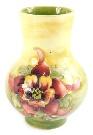 A Moorcroft Pottery small vase, decorated with purple and pink flowers on a variegated green ground, paper label to underside, 10cm high.