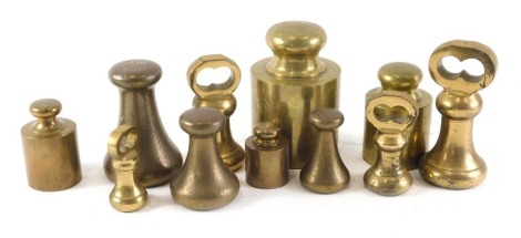 A collection of various brass bell shaped and cylindrical weights, the largest 5kg.