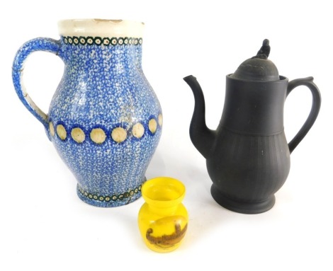 An early 20thC yellow glass Fountains Abbey jar, 8cm high, a black basalt coffee pot with figure knop, thumbnail handle, S scroll spout and fluted decoration, and a blue and white spongeware jug with green dot decoration. (3)