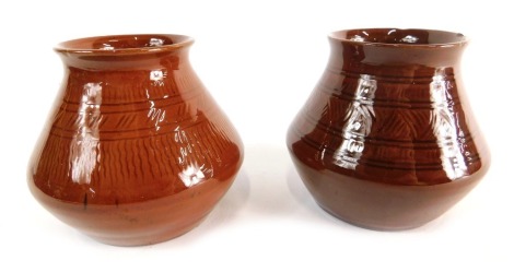 A matched pair of Linthorpe pottery vases, one initialled AW with script mark beneath of bellied circular form, in brown glazes with shaped decoration, each similar, 8cm high. (2, AF)