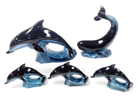 A Poole pottery figure of a dolphin, modelled riding the crest of a wave, three smaller figures of dolphins, and a figure of a whale. (5, AF)