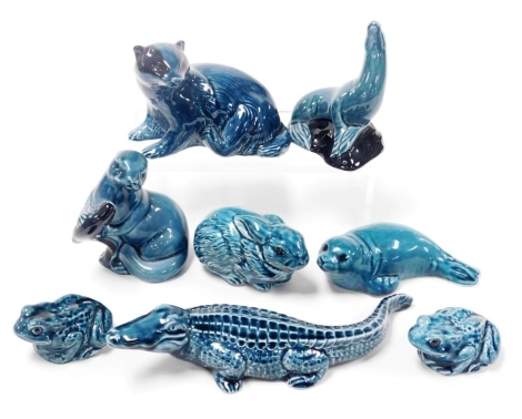 Eight Poole blue glazed pottery figures of animals and reptiles, including a crocodile, seals, and a badger.