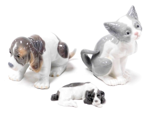 A Lladro porcelain figure of a seated puppy, another of a recumbent dog, and a Lladro figure of a seated cat. (3)