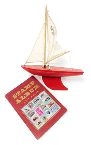 A Star Yacht pond yacht, 30cm wide, together with a stamp album containing Great Britain and world stamps.