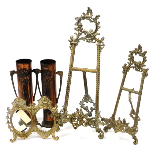 A pair of Beldray early 20thC Art Nouveau copper twin handled vases, embossed with stylised fruit and leaves, 31cm high, together with two graduated brass rococo style picture easels, 55cm and 40cm high, and a brass strut double photograph frame. (5)