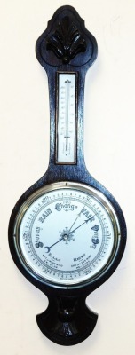 An early 20thC oak cased wheel barometer, with thermometer, the case with foliate carving, 71cm high.