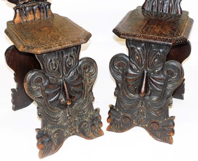 A pair of early 19thC Italian oak Sgabello hall chairs, with foliate carved crest rails, the back carved with a pair of rampant lions holding branches of pomegranates, flanking a central shield, with an engraved solid seat, raised on a grotesque mask base - 3